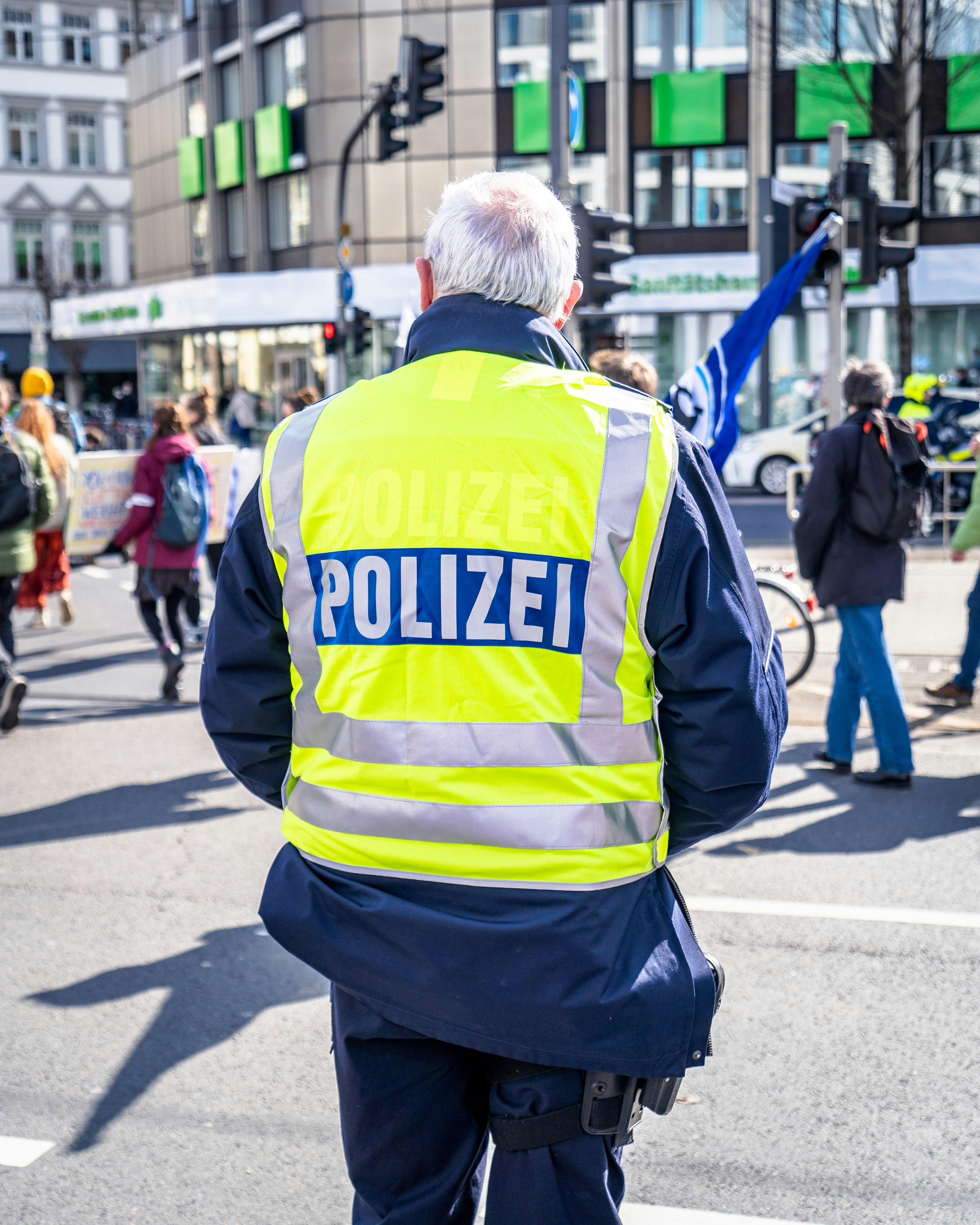 man in yellow and black jacket walking on street during daytime